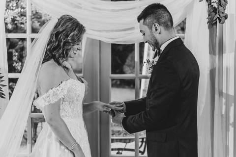 The couple exchanges vows beneath The Woodwinds’ garden arch, surrounded by blooming greenery and heartfelt emotion.'