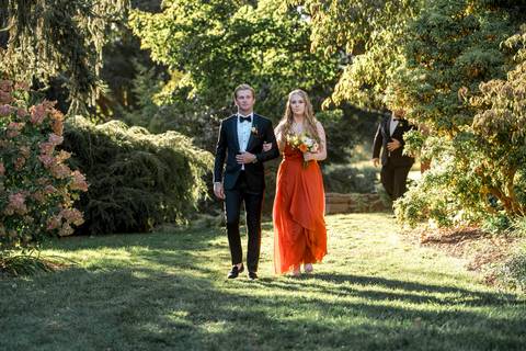 Bridesmaids walk gracefully in pastel dresses, creating a beautiful wedding party entrance at this rustic Connecticut farm wedding.'
