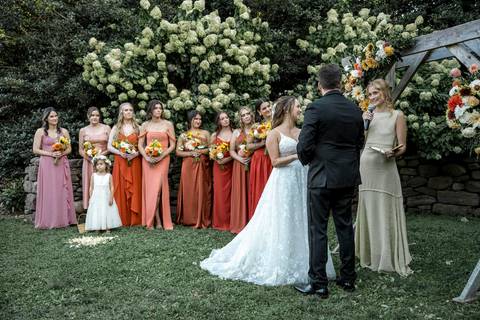 Guests watch as the couple walks down the aisle at their outdoor ceremony, framed by golden summer light at Gastler Farm in Connecticut.'