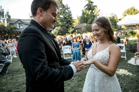 Guests watch as the couple walks down the aisle at their outdoor ceremony, framed by golden summer light at Gastler Farm in Connecticut.'