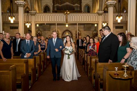 Guests gather quietly at the church entrance as soft light spills through the doors. The anticipation is palpable, a gentle stillness before the ceremony begins, setting the tone for an emotional and intimate celebration.
Vanessa Trettel Photography'