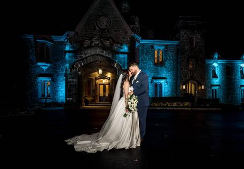 Artistic silhouette of the bride and groom against the deep blue night sky at Whitby Castle, expert lighting by Vanessa Trettel Photography.'