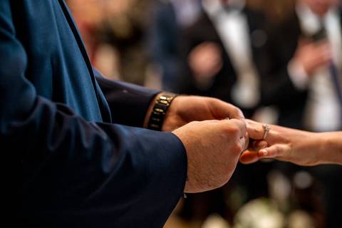 The couple placing rings on each other’s fingers, symbolizing their union during the indoor ceremony at Whitby Castle, photo by Vanessa Trettel Photography.'