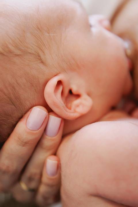 detalhe da orelha do bebê enquanto mama'