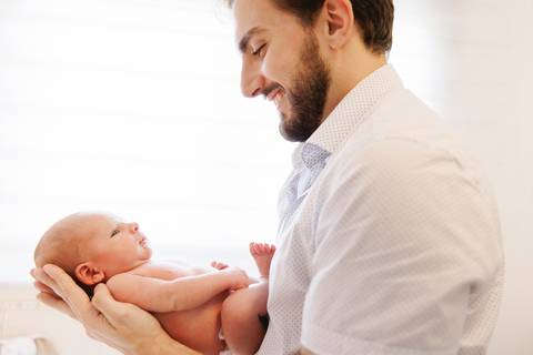 bebê no colo do pai no contraluz da janela'