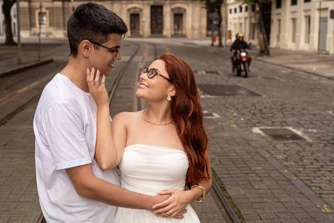 Júlia e Leonardo trocam olhares e carinhos em uma rua histórica do Centro do Rio de Janeiro.'