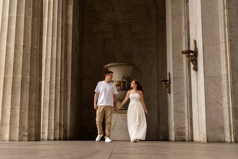 Júlia e Leonardo caminham entre grandes colunas de um edifício histórico durante ensaio pré casamento no Rio.'