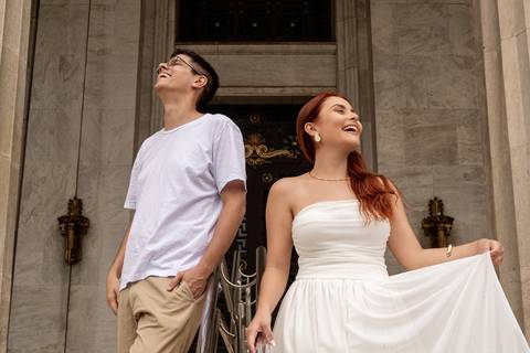 Júlia e Leonardo sorriem diante de uma construção histórica durante seu ensaio pré wedding no Rio de Janeiro.'