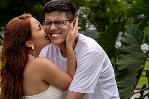 Júlia abraça Leonardo e os dois sorriem entre as folhagens durante ensaio pré casamento no Rio de Janeiro.'