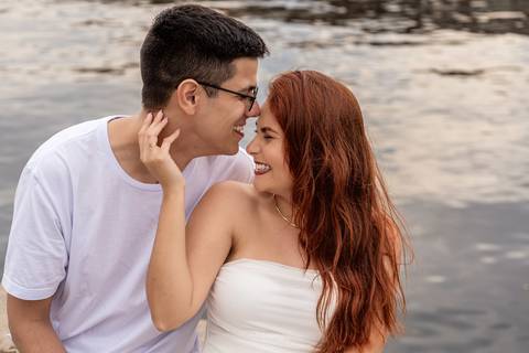 Júlia e Leonardo trocam olhares carinhosos à beira da água durante ensaio de casal no Rio de Janeiro.'