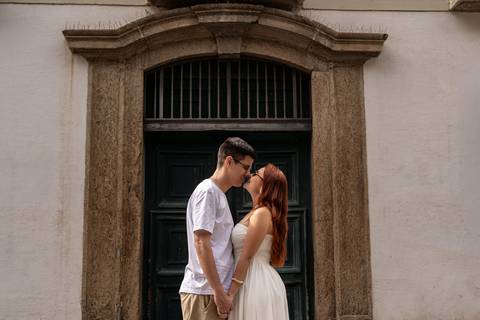 Júlia e Leonardo se beijam diante de uma porta histórica durante ensaio de casal no Centro do Rio.'