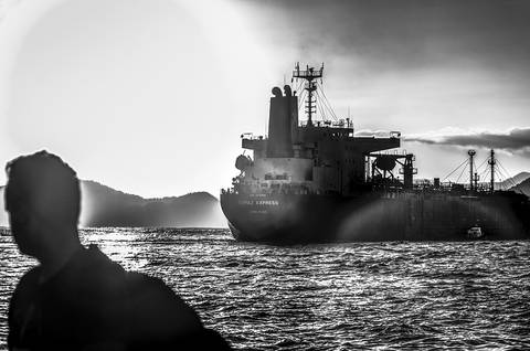 Pedestre e navio lado a lado em Santos-SP'