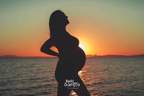 Silhueta de mulher gravida, rio guaíba ao fundo'