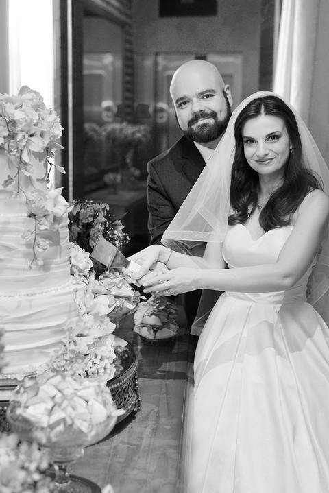 Foto em pb, noivos cortando o bolo'