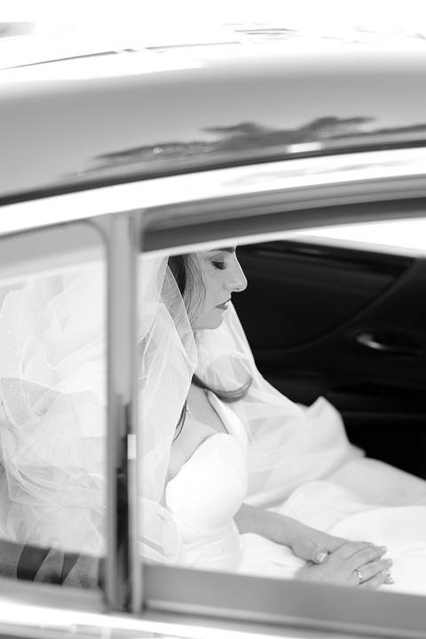 Foto em pb, noiva sentada no carro com os olhos fechados, meditando'