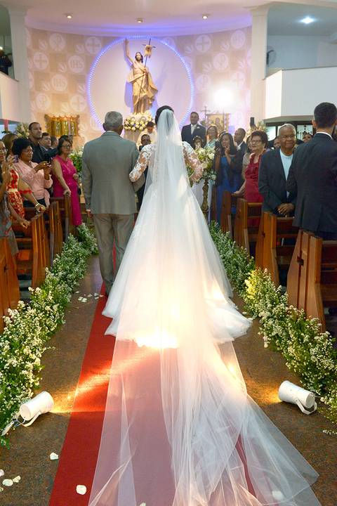 Vista de trás, com o véu pelo corredor da igreja a noiva e o pai em direção ao altar'