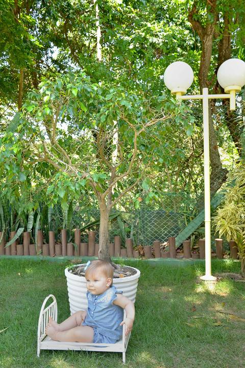 bebê sentada numa caminha de ferro retrô em um jardim'