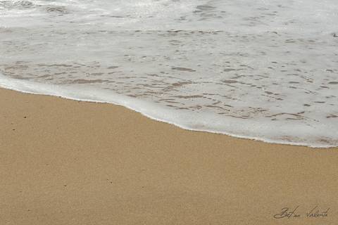 foto em cores movimento da espuma do mar desenhandada na areia'