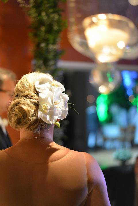 Foto em cor - detalhe do penteado e flor na cabeça da noiva'
