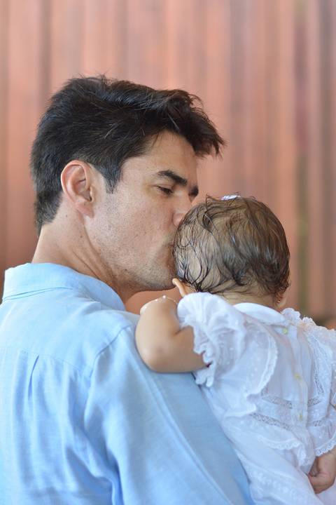 linda foto colorida do padrinho beijando a cabeça da afilhada'