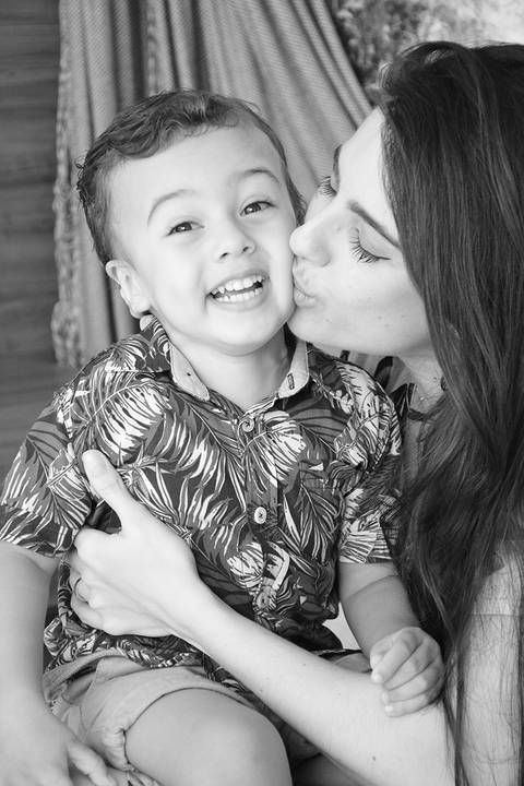Mãe beija amorosamente o rosto do filho em foto pb'
