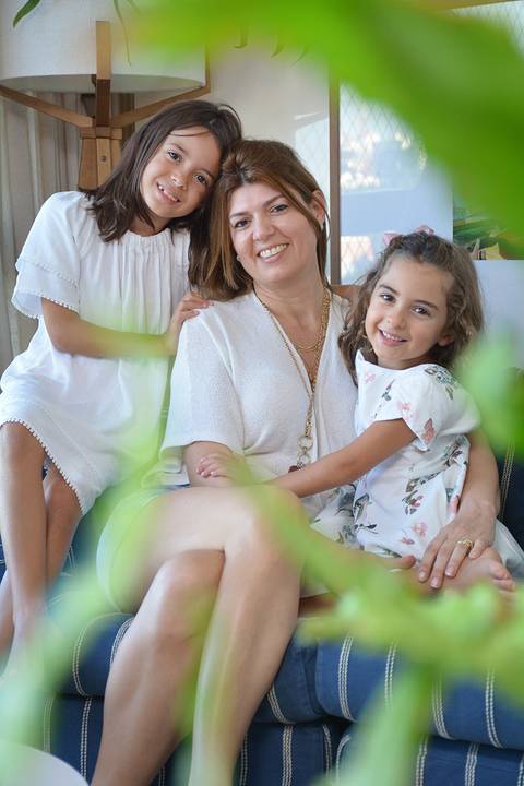 Mãe e filhas posam sorridentes'