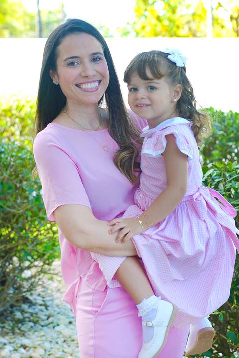 Mãe com sua filha no colo vestem cor de rosa'