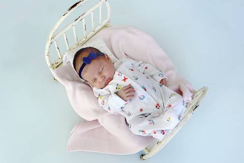 Foto feita de cima da bebê numa mini cama'