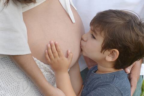 Fotografia em close do beijo do irmão mais velho na barriga da mamãe'