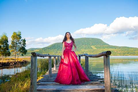 Ensaio de 15 anos com vestido vermelho realizado em Osório na pousada Temática Encantos do Sul com céu azul'