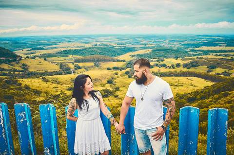 Ensaio pré wedding casal de branco com mãos dadas em vista panorâmica de morro em Botucatu - SP'