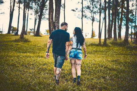 Ensaio pré wedding casal caminha em bosque com grama verde em Botucatu - SP'