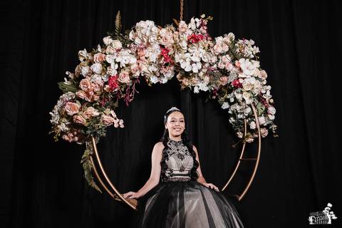 Retrato de debutante em balanço florido na festa, com fundo totalmente preto'