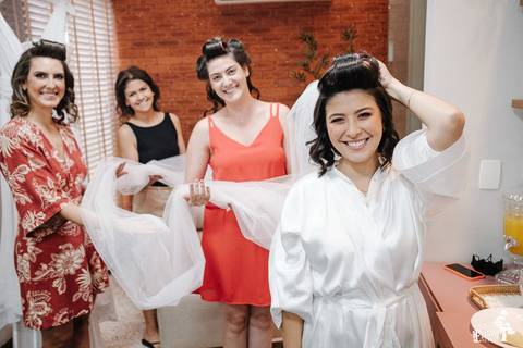 madrinhas com a noiva, segurando o véu que todas usaram para casar'