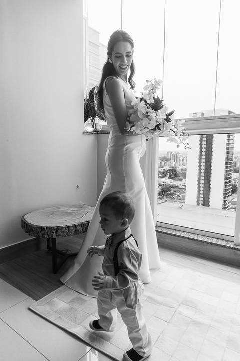 Foto da noiva em preto e branco com criança correndo a frente dela'