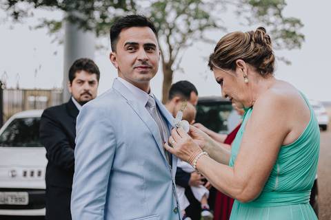 Foto da sogra ajudando o noivo a colocar a lapela no terno'