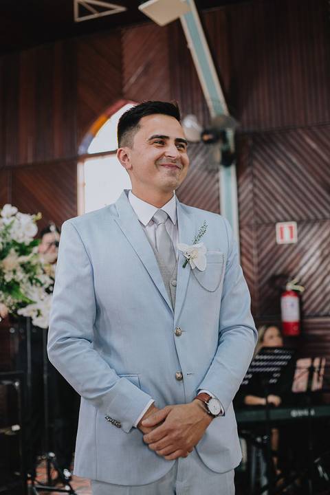 Foto do noivo vendo a noiva chegar na cerimônia sorrindo ansioso'