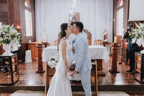 Foto do casal durante a cerimônia de matrimônio na Capela Nossa Senhora Aparecida, no momento do beijo'