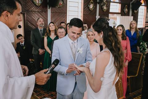 Foto do casal durante a cerimônia de matrimônio na Capela Nossa Senhora Aparecida, no momento da troca de alianças'