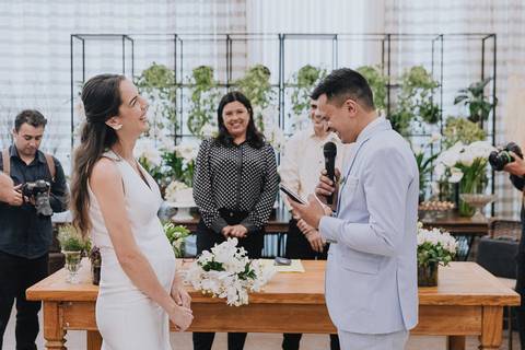 Foto do casamento civil no Espaço Atlanta, durante os votos do noivo, com a noiva sorrindo muito'