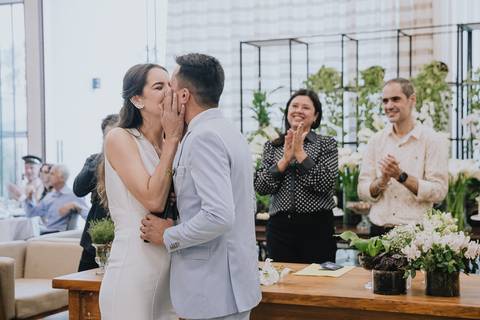 Foto do casamento civil no Espaço Atlanta, durante o momento do beijo com a juiza de paz e o escrivão aplaudindo'
