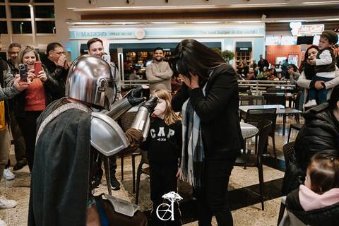 noiva surpreendida em pedido de casamento geek inspirado em star wars, the mandalorian, noivo ajoelhado segurando as alianças, vestido de mandaloriano'