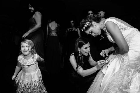 Casamento na chácara Carpe Diem, em são josé dos pinhais, curitiba, paraná, convidada pegando o coração da barra do vestido de noiva, com criança dançando ao lado'