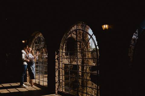 Casal em ensaio pré-wedding na Vinícola La Dorni em Bandeirantes, PR, entre arcos de pedra e janelas antigas iluminadas pela luz natural, em clima leve e artístico'
