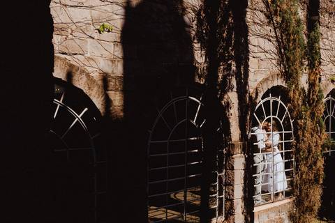 Casal em ensaio pré-wedding na Vinícola La Dorni em Bandeirantes, PR, entre arcos de pedra cobertos por trepadeiras, iluminados pela luz natural em composição artística'