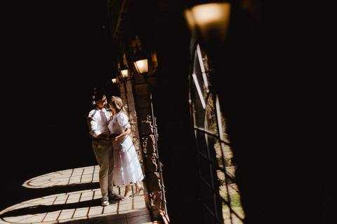 Casal em ensaio pré-wedding na Vinícola La Dorni em Bandeirantes, PR, iluminado pela luz natural entre arcos de pedra, em cena romântica e artística com contrastes de sombra e brilho'