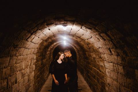 Casal em ensaio pré-wedding na Vinícola La Dorni lado a lado no túnel de pedras iluminado, em clima intimista e cinematográfico'