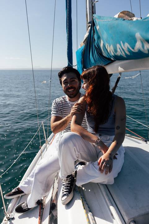 Arthur e Mari rindo juntos a bordo do veleiro Limonada em alto-mar, durante navegada do ensaio pré-wedding'