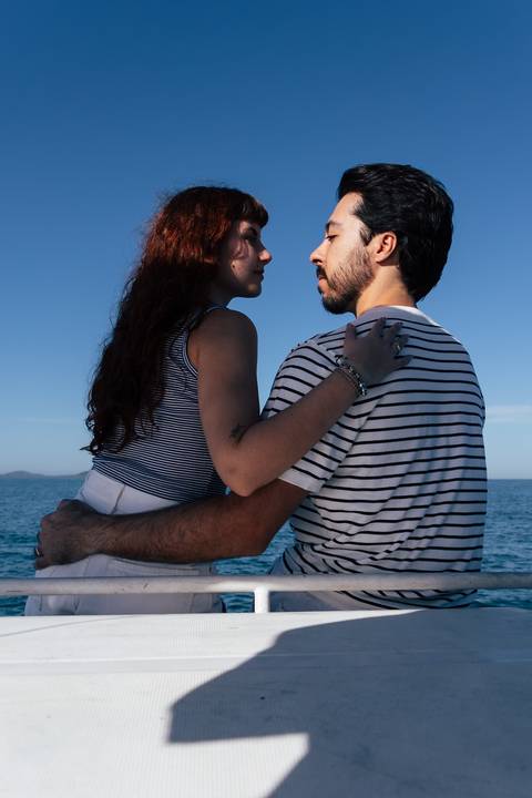 Casal abraçado de costas para a câmera observando o horizonte do mar durante pré-wedding em veleiro'