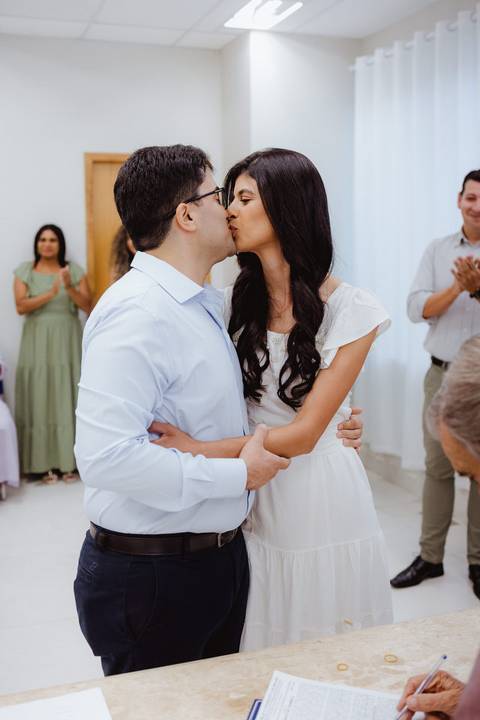 Nathan e Thamires se beijando na cerimonia civil, convidados aplaudindo desfocados ao fundo'